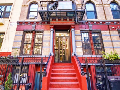 the front of a building with red steps and a red door